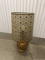 Full view of large vintage table lamp with gold-toned metal base and geometric patterned glass shade.