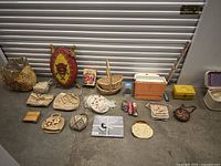 Full view of miscellaneous collectibles including woven tribal shield, toy banks, small baskets, decorative plates and assorted small carved items.