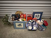 Wide shot showing entire miscellaneous lot including framed art, dishware, and plastic totes with assorted items