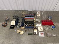 Photo showing assorted jewelry pieces laid out including brooches, rings, small boxes, and bracelets.