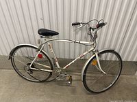 Side view of the full white vintage road bicycle showing frame, wheels, pedals, and seat.
