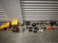 Overview of all cameras, cases, film boxes, straps and accessories laid on concrete floor