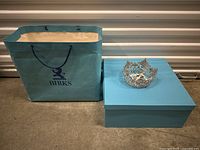 Photo of Birks paper bag, light blue box, and vintage silver-tone crown on concrete floor.