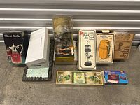 Photo showing various vintage items including claret bottle, boxed appliances, ceramic cups, and vintage metal jam spoon holder