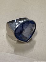 Side angle of vintage sterling silver ring showing blue faceted stone and front face with 925 silver stamp inside band.