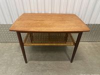 Front view showing rectangular teak top and cane shelf