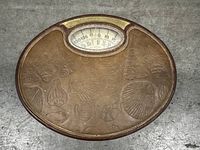 Oval vintage mechanical scale with embossed sea shell and ocean motifs, dial weight display at top center