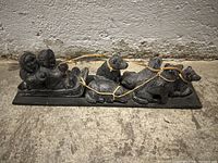 Photo of six dark stone animal figurines arranged on a rectangular base with yellow string tying them.