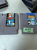 Photo of two vintage Nintendo NES game cartridges: one showing Super Mario Bros. and Duck Hunt label, the other showing Fester's Quest label.