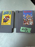 Photo showing two vintage Nintendo NES game cartridges Super Mario Bros 3 and Dr. Mario on a light surface.