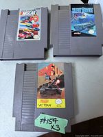 Photo showing Nintendo NES cartridges for NASCAR, Silent Service, and Conflict games