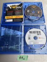 Opened case of Infamous Second Son showing disc and inner artwork, alongside opened case of The Last of Us Part I showing game disc