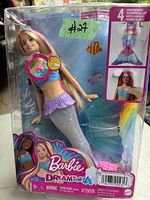 Barbie Dreamtopia mermaid doll in sealed original packaging. Doll has long blonde hair, blue top, purple skirt and silver mermaid tail with glitter. Box shows artwork and details on features.