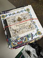 Stack of adult coloring books showing different cover designs including floral and thematic artwork