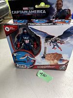 Boxed new in box Marvel Studios Captain America: Brave New World action figure with wings and shield, depicted with fist launcher accessory on packaging.