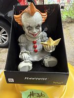 Pennywise Horror Babies figurine seated in black box holding yellow paper boat. Shows detailed molding and paint of character in baby form.