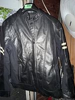 Front view of black leather jacket hanging on hanger