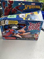 Box of Marvel Spider-Man Real Webs 2-in-1 web shooter toy in sealed packaging with branding and product details visible.