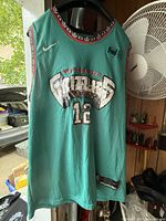 Front view of teal Nike basketball tank top with Memphis Grizzlies logo and number 12 on front, showing patterned neckline and armholes