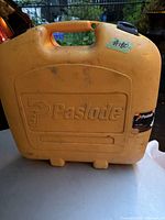 Closed yellow hard plastic Paslode carrying case with handle and logo visible