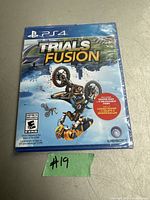 Photo of sealed PS4 game Trials Fusion cover art, showing motorbike stunt and Ubisoft branding.