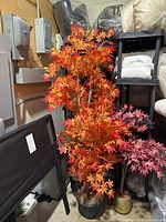 Full view of artificial maple tree showing orange-red leaves and black woven pot.