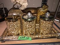 Set of three gold glitter lidded canisters on mirrored tray alongside gold decorative items