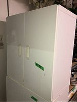 Photo showing full white storage cabinet with two doors, side view indicating dimensions and condition.