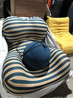 Front view of striped lounge chair with navy pouf resting on seat