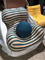 Front view of striped lounge chair with teal pouf positioned on seat