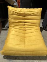 Front view of mustard yellow lounge chair showing contoured tufted seat and back