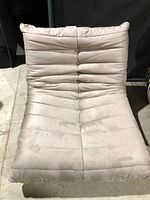 Front view of the beige fabric lounge chair showing button tufting and stitched segments on upholstery.