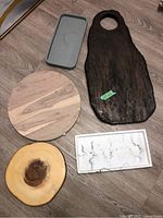 Overview of five assorted charcuterie boards and trays including dark wooden board with handle, round wooden board, wood slice, white marbled tray, and gray tray.