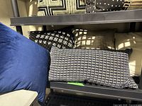 Rectangular gray geometric patterned cushion, black and white cushions stacked beneath