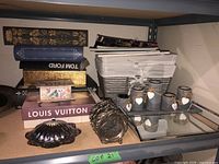 Shelf with staged items including faux books, baskets, mirrored tray, and decorative candle holders.