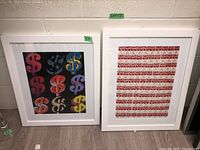 Two framed prints side by side on floor with white frames. One with colorful dollar signs, the other with soup cans.