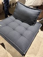 Front angle of the anthracite modular armless chair showing the tufted seat and padded back cushion.
