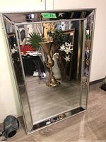 Full view of the mirror leaning against a wall showing its rectangular shape and reflective surface.