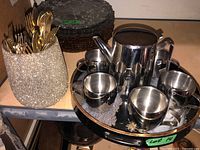 Overall view of the tea set on serving tray accompanied by gold cutlery and black plates