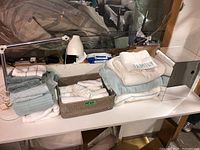 Full view of the lot showing towels, basket, lamp, and mirror on a white surface with a mirror in background.