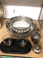Overall view of the lot showing two mirrored trays, two glasses on a small black tray, silver pineapple, and a round silver container