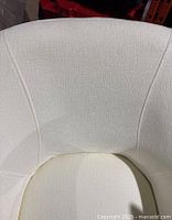 Close-up image showing the white textured upholstery and seat cushion of one chair with visible soiling.