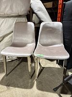 Two matching chairs with light gray fabric upholstery and chrome legs, showing overall soiling and wear.