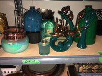 Photo showing multiple blue, teal, green decorative vases, containers and bird sculptures.