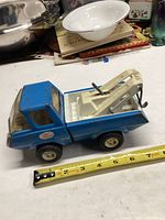 Blue Tonka tow truck toy approximately 9 inches long, placed next to measuring tape to show size and condition.