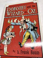 Front cover of Dorothy and the Wizard in Oz book showing illustrated scene with Dorothy, the man, and small animals.