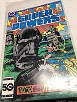 Cover of Super Powers comic book number 3 showing several superheroes and a Moai statue illustration.
