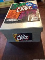White box labeled 'Dead Last' with the game rule booklet placed on top, showing box wear and sticker labeling.
