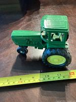 Side view of green John Deere toy tractor with measuring tape showing 7.5 inches length