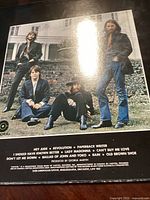 Album back cover showing The Beatles sitting outdoors, listing tracks including Hey Jude, Revolution, Paperback Writer, and others. Produced by George Martin, Capitol Records.
